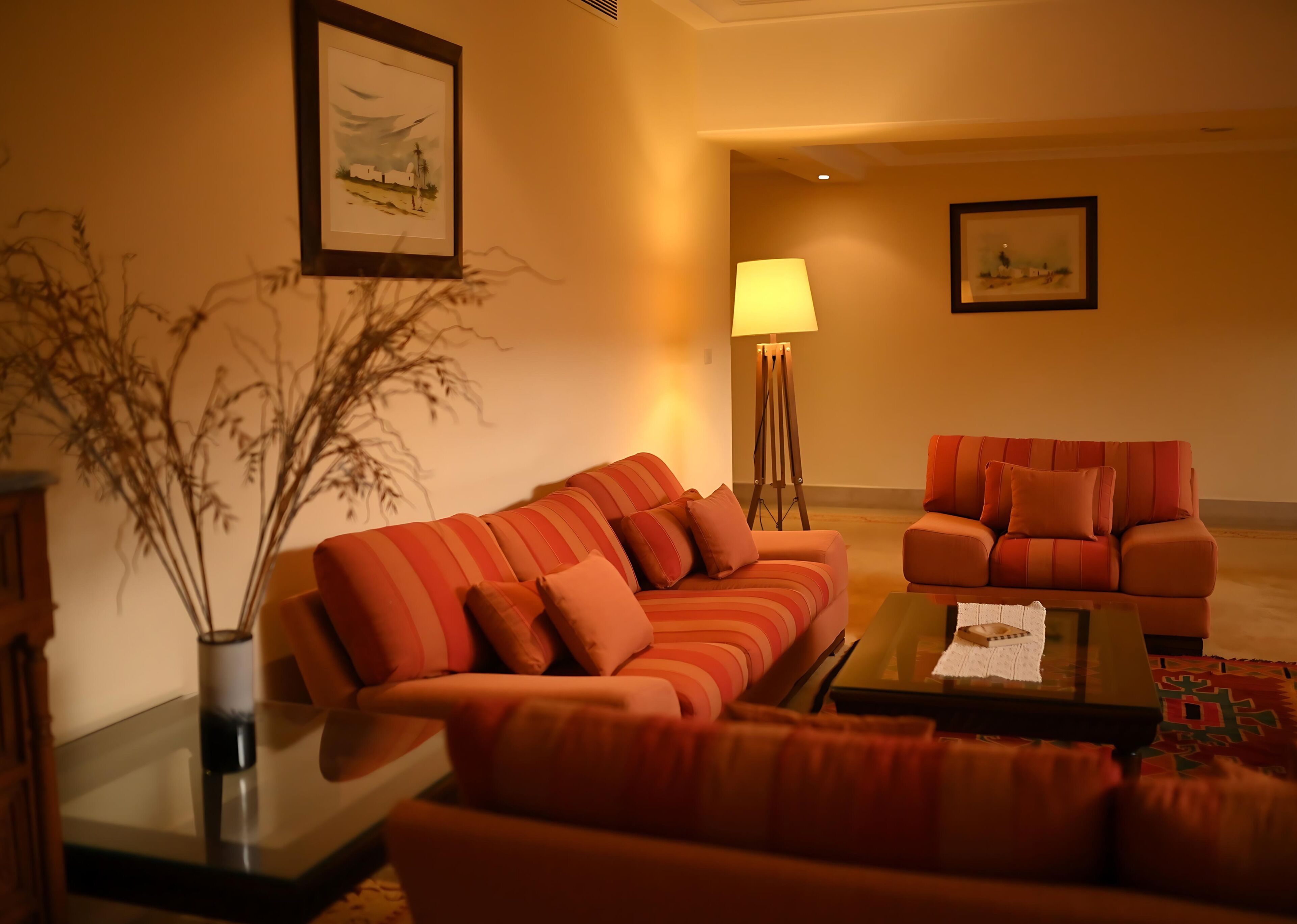A living room with two couches, a floor lamp, and framed artwork on the walls.