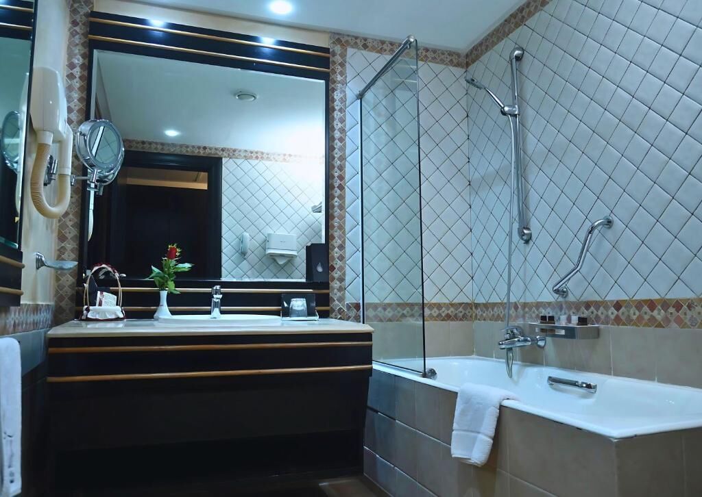 A modern bathroom with a large mirror, a vanity with a sink, a bathtub, and a shower area.