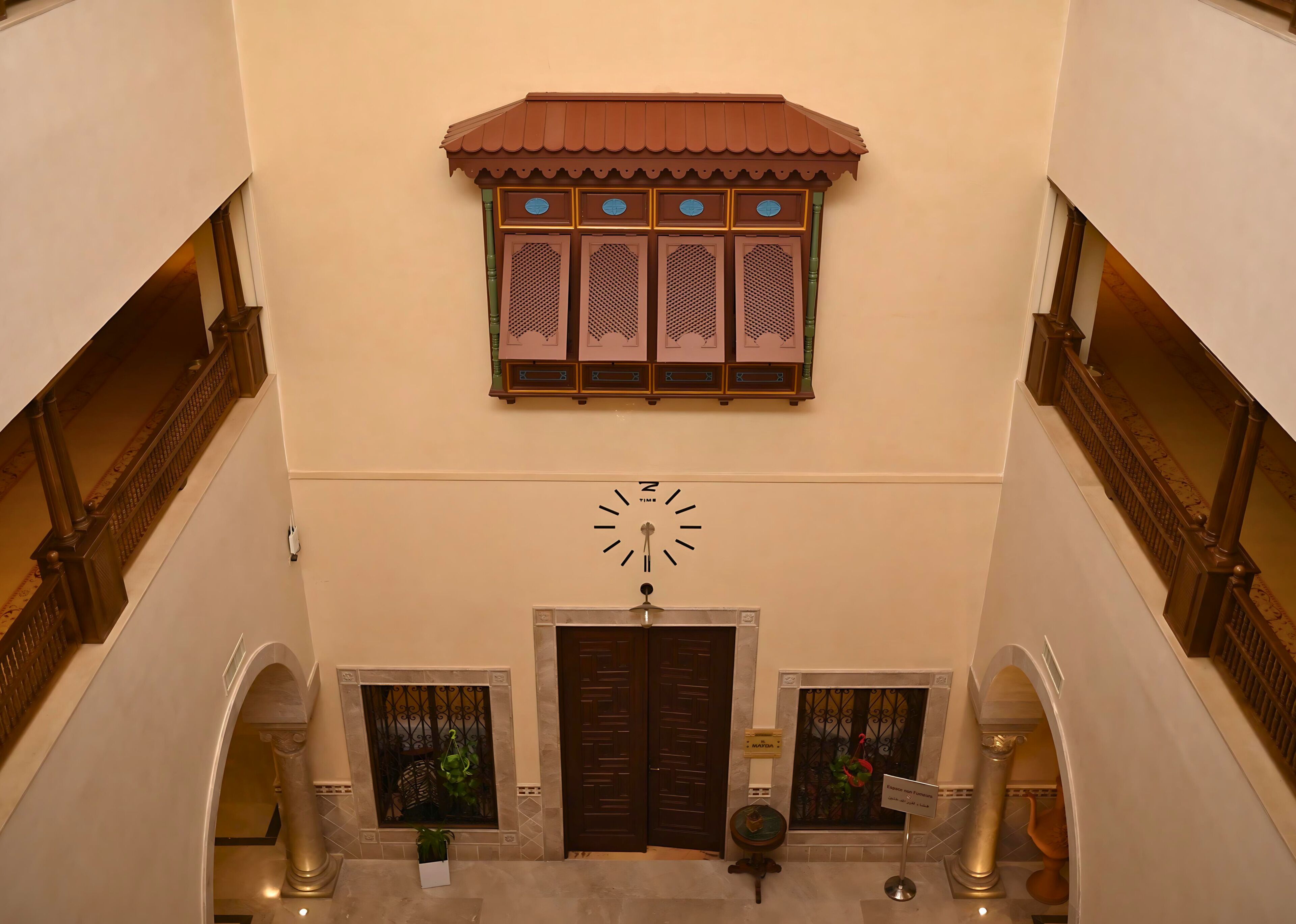 A staircase with a clock and decorative elements, including a window with traditional shutters and a door with a metal gate.
