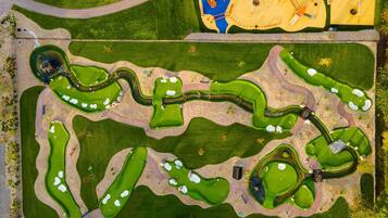 An aerial view of a golf course with multiple greens, bunkers, and a water hazard.