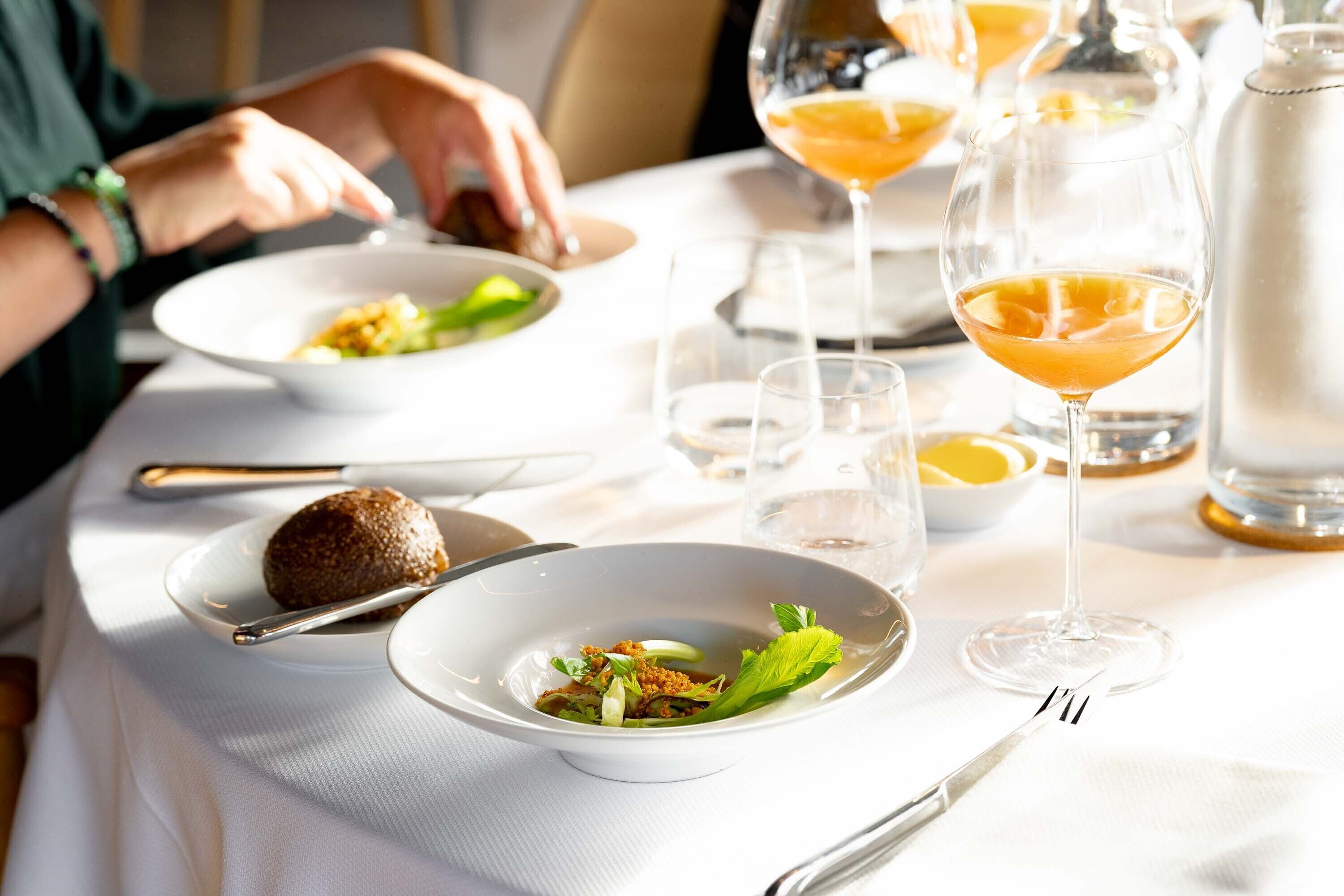 Una mesa de comedor con diversos platos y copas de vino.