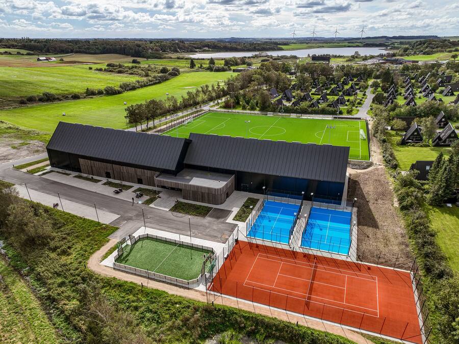Un edificio grande con varias instalaciones deportivas, incluyendo un campo de fútbol, canchas de tenis y una piscina.