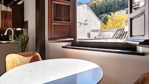 Una cocina moderna con armarios de madera oscura, encimera blanca y ventana con vistas a un paisaje urbano de edificios y árboles.