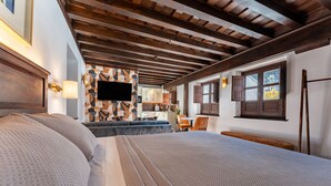 Habitación de hotel con una cama grande, un televisor montado en la pared, una zona de cocina y una ventana con vistas.