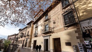 Una calle adoquinada con edificios históricos, un cartel que indica 'Hotel Ramallo' y una tienda con ropa exhibida en el exterior.