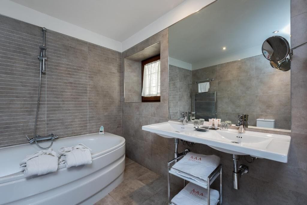A modern bathroom with a freestanding bathtub, a large mirror, and a vanity with a sink and countertop.