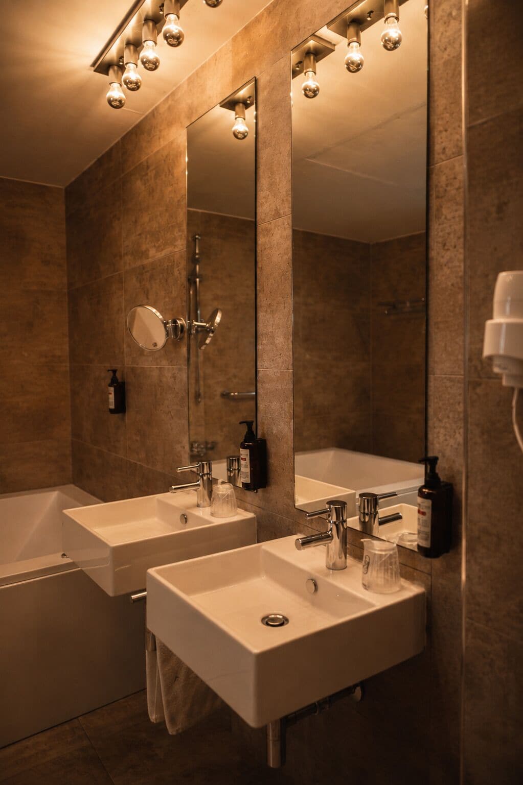 Un baño moderno con dos lavamanos, un espejo grande y una bañera.