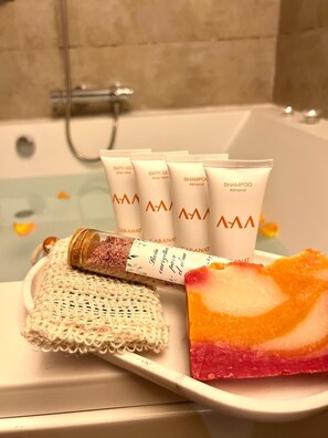 A bathroom with a bathtub, a tray with bath products, and a decorative item. - Gar Anat Hotel Boutique - Domus Artis.  (Granada)