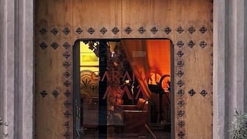 Une porte en bois avec un panneau de verre, un blason au-dessus, et le reflet de l’éclairage intérieur.