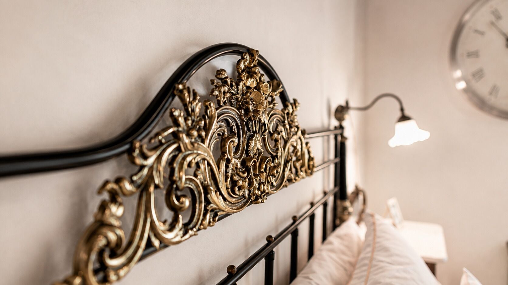 A bed with an ornate metal headboard and a bedside lamp.
