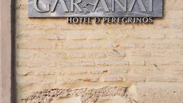A sign for GARANAT HOTEL D PEREGRINOS on a textured wall.