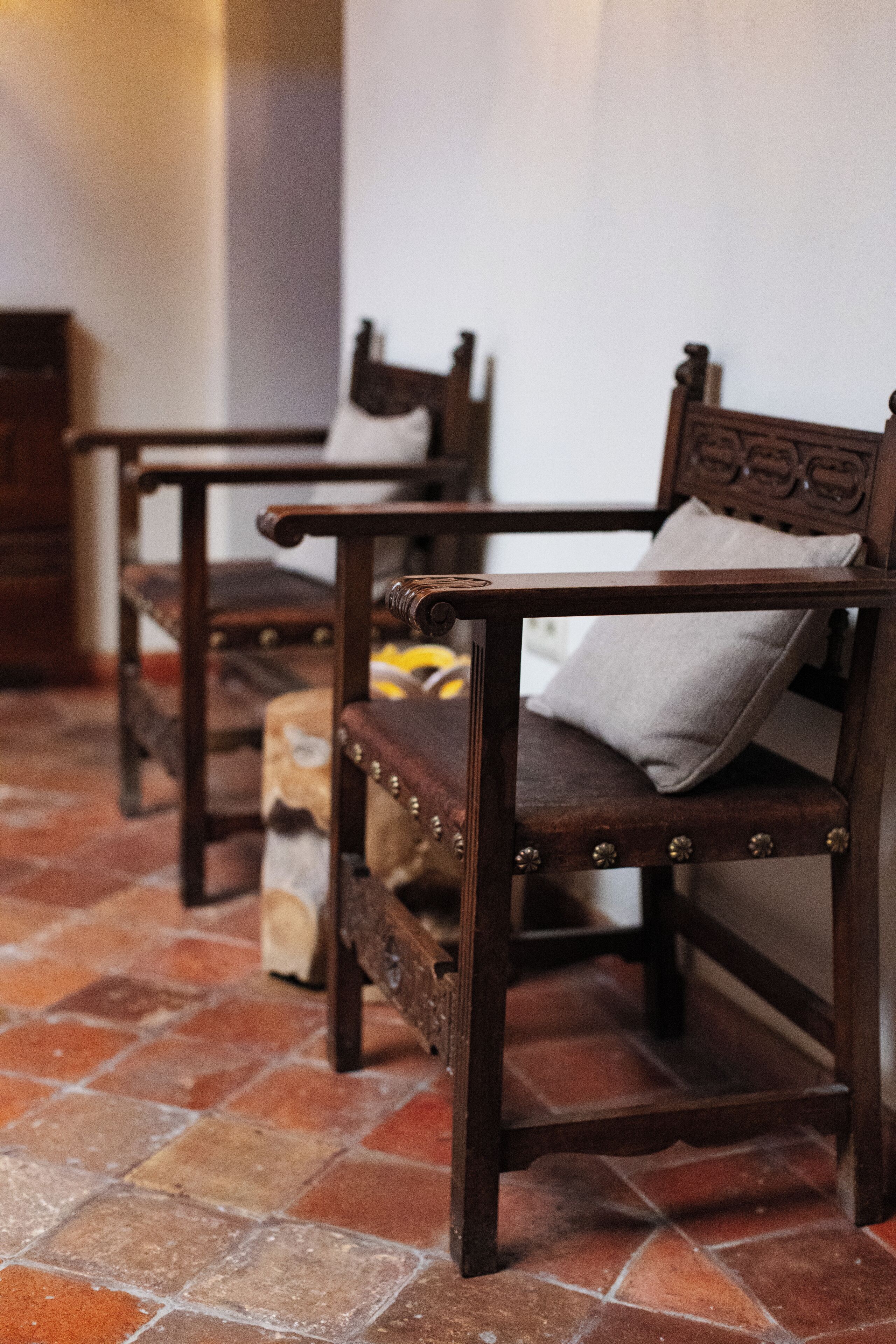A row of wooden chairs with cushioned seats and backs, positioned on a tiled floor.