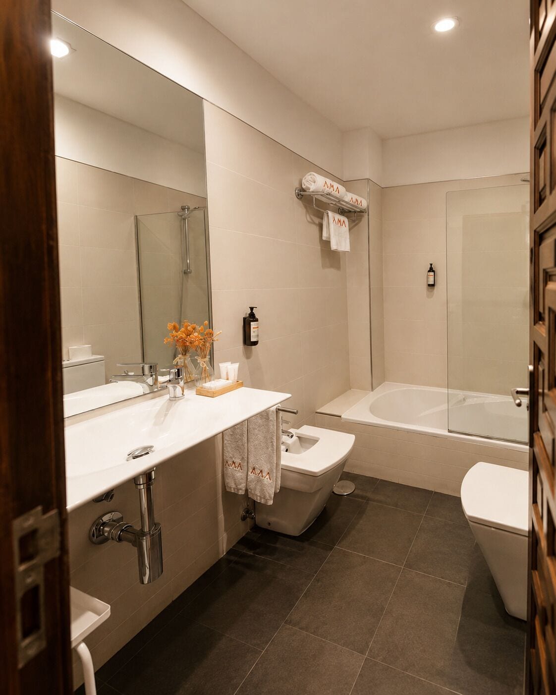 A modern bathroom with a double sink, a toilet, a bathtub, and a glass shower enclosure.
