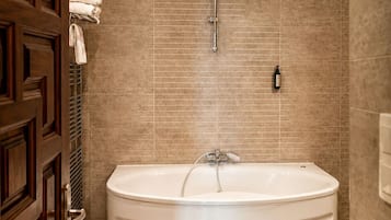 Un baño con bañera independiente, inodoro y perchero.