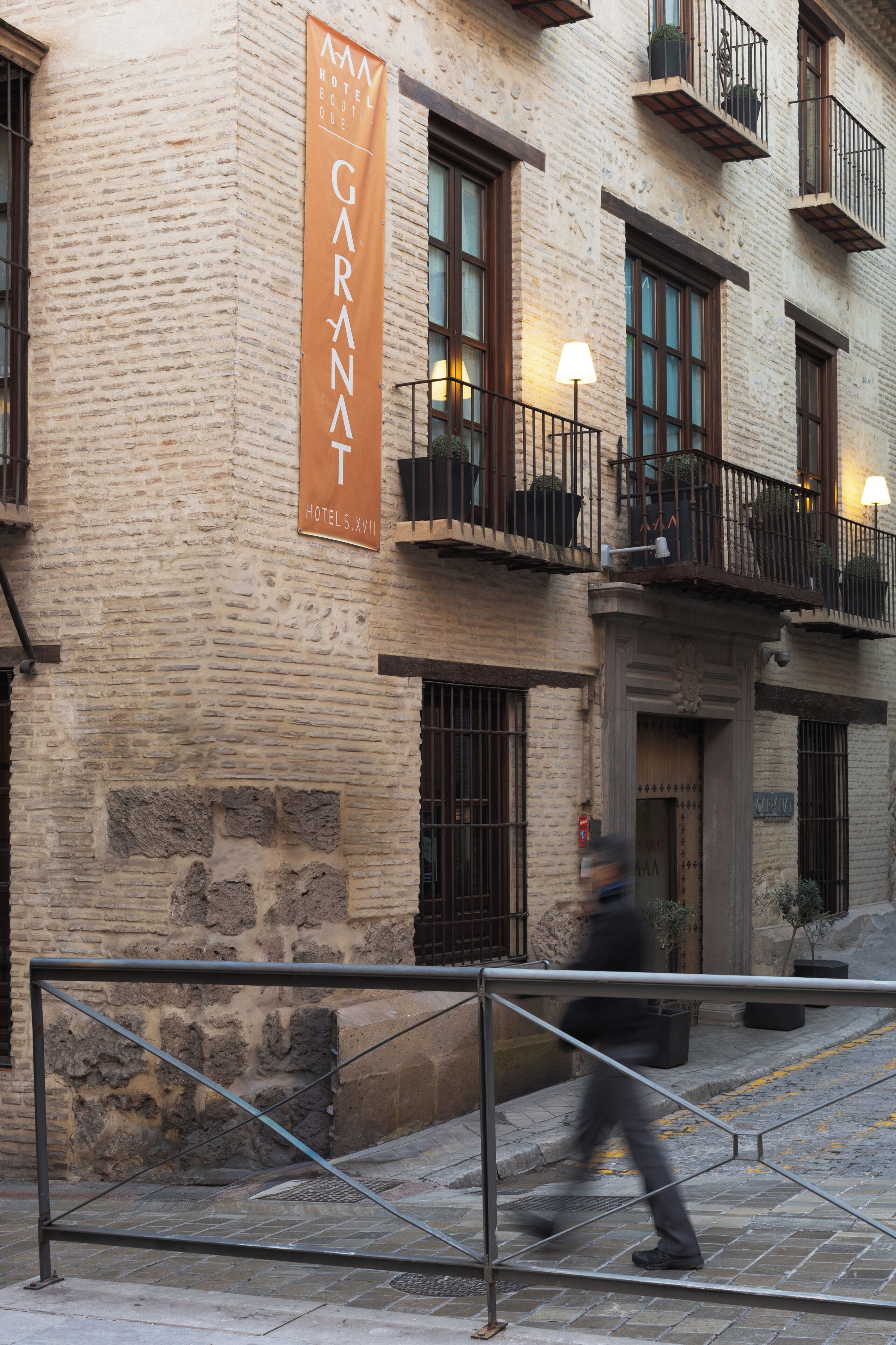 A hotel facade with a prominent banner, balconies with plants, and a pedestrian walkway.
