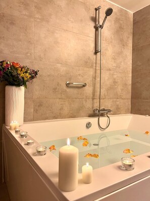 A bathtub with a showerhead, candles, and flower petals. - Gar Anat Hotel Boutique - Domus Artis.  (Granada)
