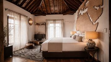 Un dormitorio con una cama grande, techo de madera, un mapa en la pared y una lámpara de noche.