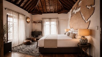 A bedroom with a large bed, a wooden ceiling, a map on the wall, and a bedside lamp.