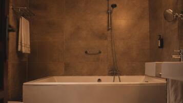 A modern bathroom with a freestanding bathtub, a showerhead, and a toilet.