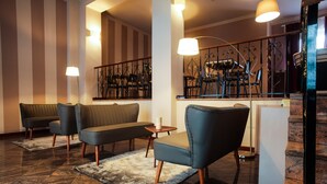 Un vestíbulo con zona de estar que incluye sofás, sillones, un piano y una escalera.