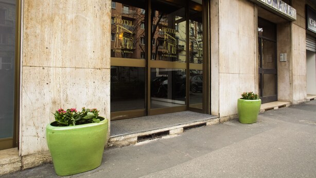 La entrada de un hotel con amplias puertas de cristal y un letrero que dice "HOTEL ROMANIA".