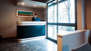 Un mostrador de recepción de hotel con un amplio ventanal, un cuadro enmarcado y una decoración interior moderna.