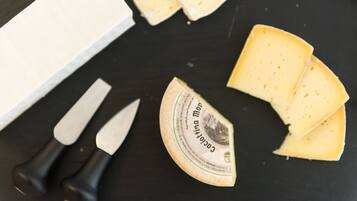 Una rueda de queso, un cuchillo y rebanadas de queso sobre una superficie negra.