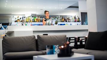 A modern bar area with a variety of liquor bottles, a bar counter, and a seating area with a sofa and a coffee table.