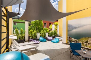 Un patio al aire libre con asientos, una mesa y vistas a un paisaje montañoso.