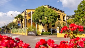 A yellow building with a sign reading "HOTEL SANFONI" and a stop sign nearby. - Hotel Santoni Freelosophy (Nago-Torbole)