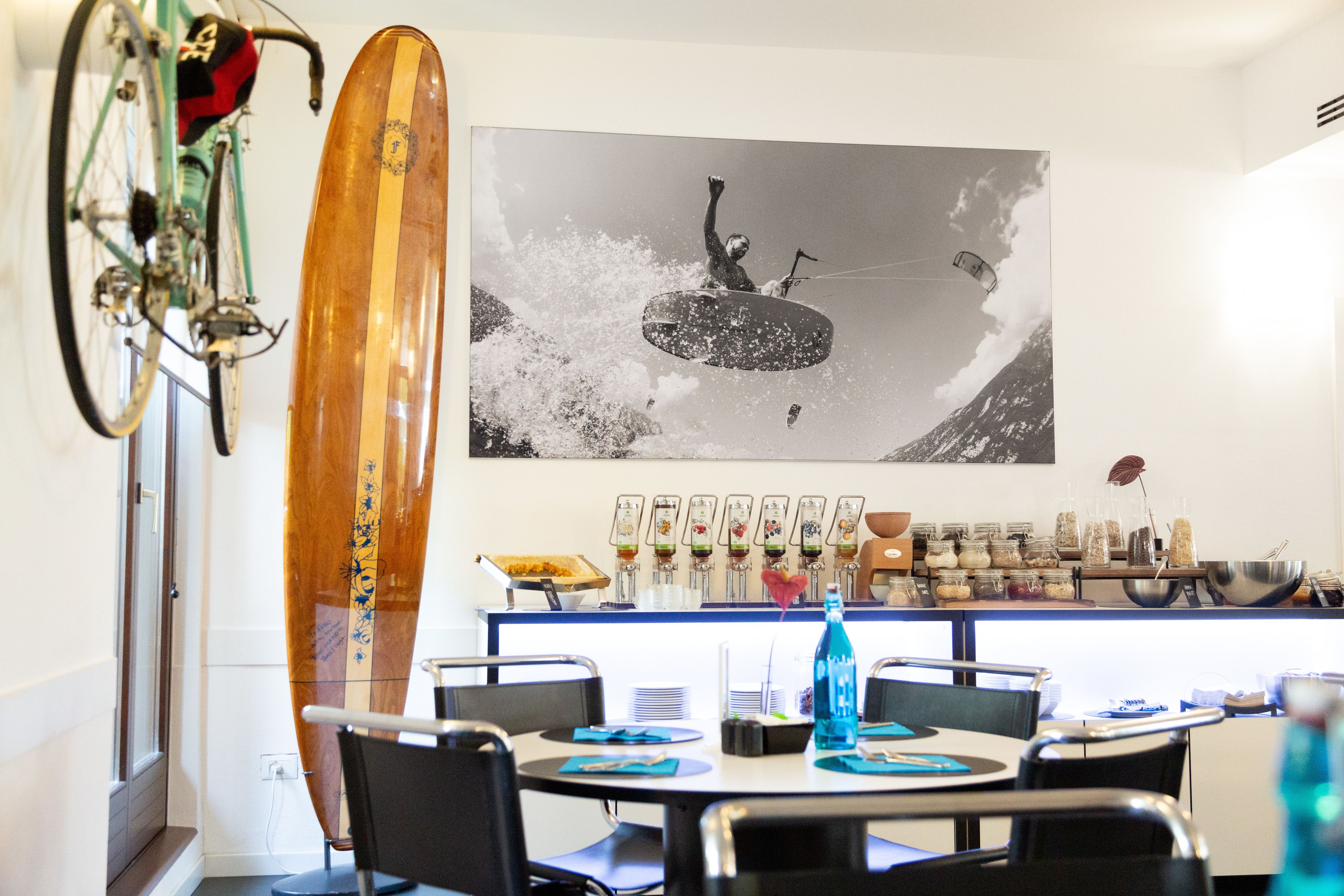 A dining area with a table set for four, a surfboard, and a wall-mounted bar with various bottles and glasses.