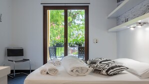 A hotel room with a bed, towels, a chair, and a view of greenery outside. - Hotel Santoni Freelosophy (Nago-Torbole)