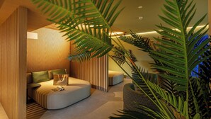 A modern, cozy room with a curved sofa, a small table, and a large potted plant. - Hotel San Giorgio (Caorle)
