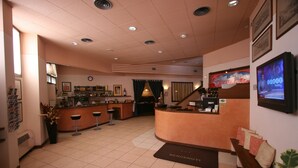 Un vestíbulo de hotel con recepción, zona de bar y asientos.