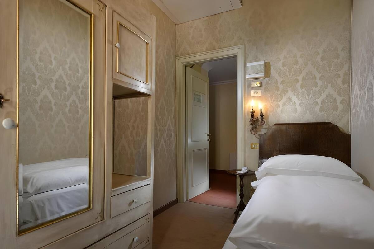 Une chambre d’hôtel comprenant un lit, une commode, un miroir et une porte donnant sur une autre pièce.