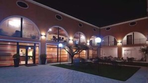 A courtyard with arched windows and a central tree, surrounded by a brick pathway. - Hotel Villa Altura (Ospedaletto Euganeo)