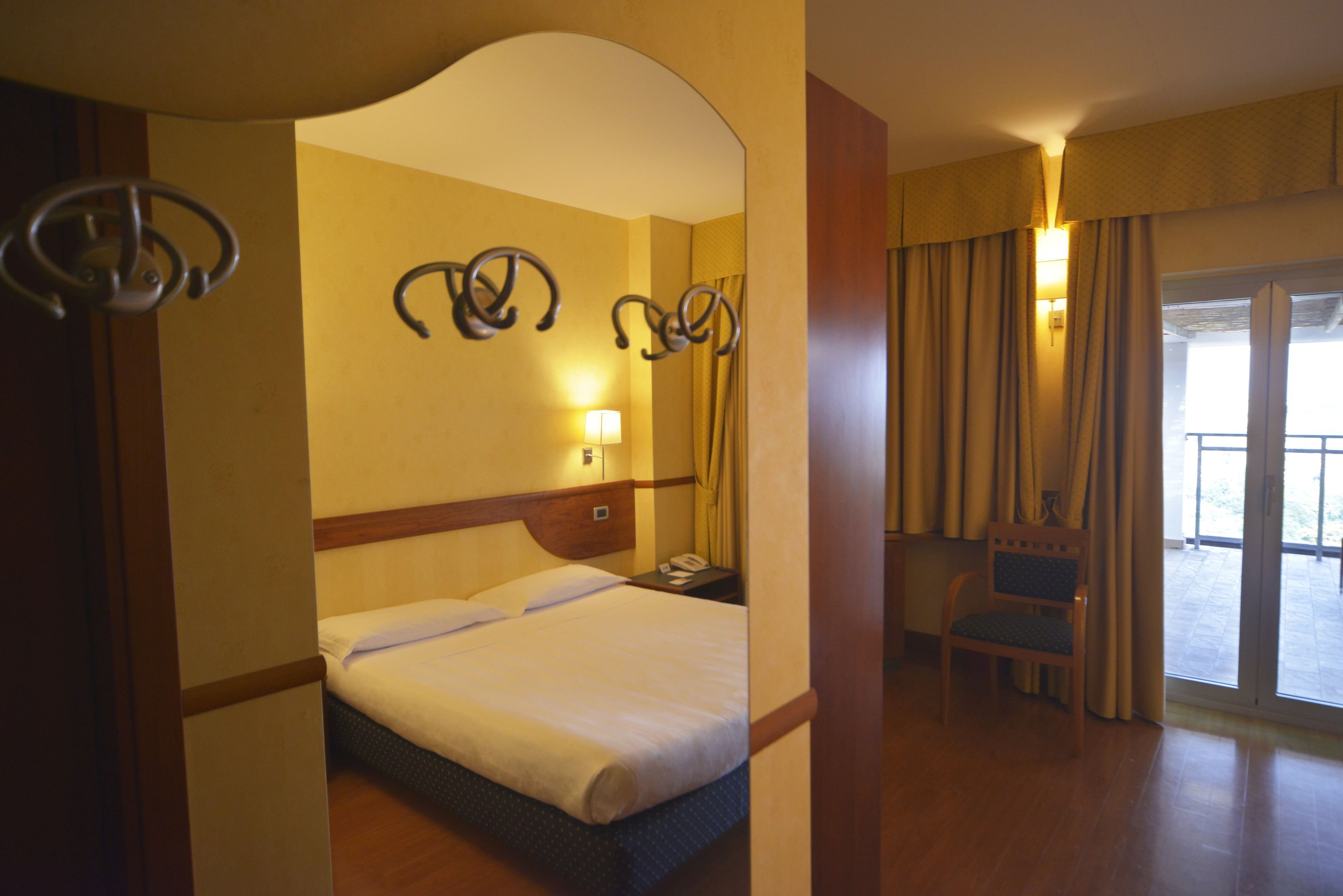 Ein Hotelzimmer mit Bett, Sessel, Schreibtisch und einem großen Spiegel.