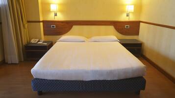 A hotel room with a large bed, two bedside lamps, a telephone, and a nightstand.