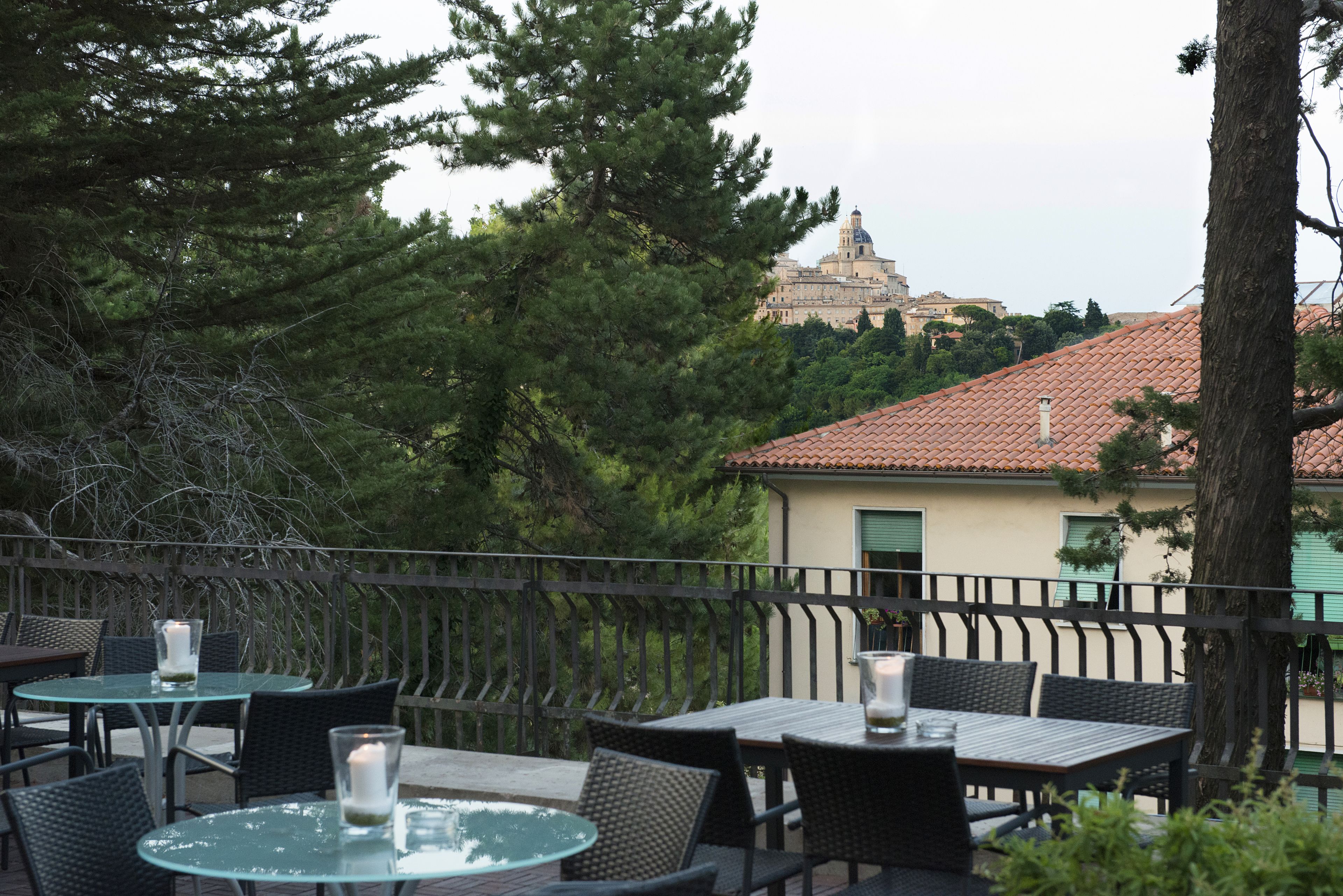 An outdoor patio with tables and chairs, a railing, and a view of a historic building with a dome in the background.