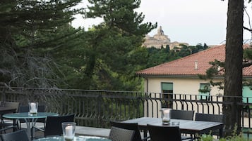 An outdoor patio with tables and chairs, a railing, and a view of a historic building with a dome in the background.