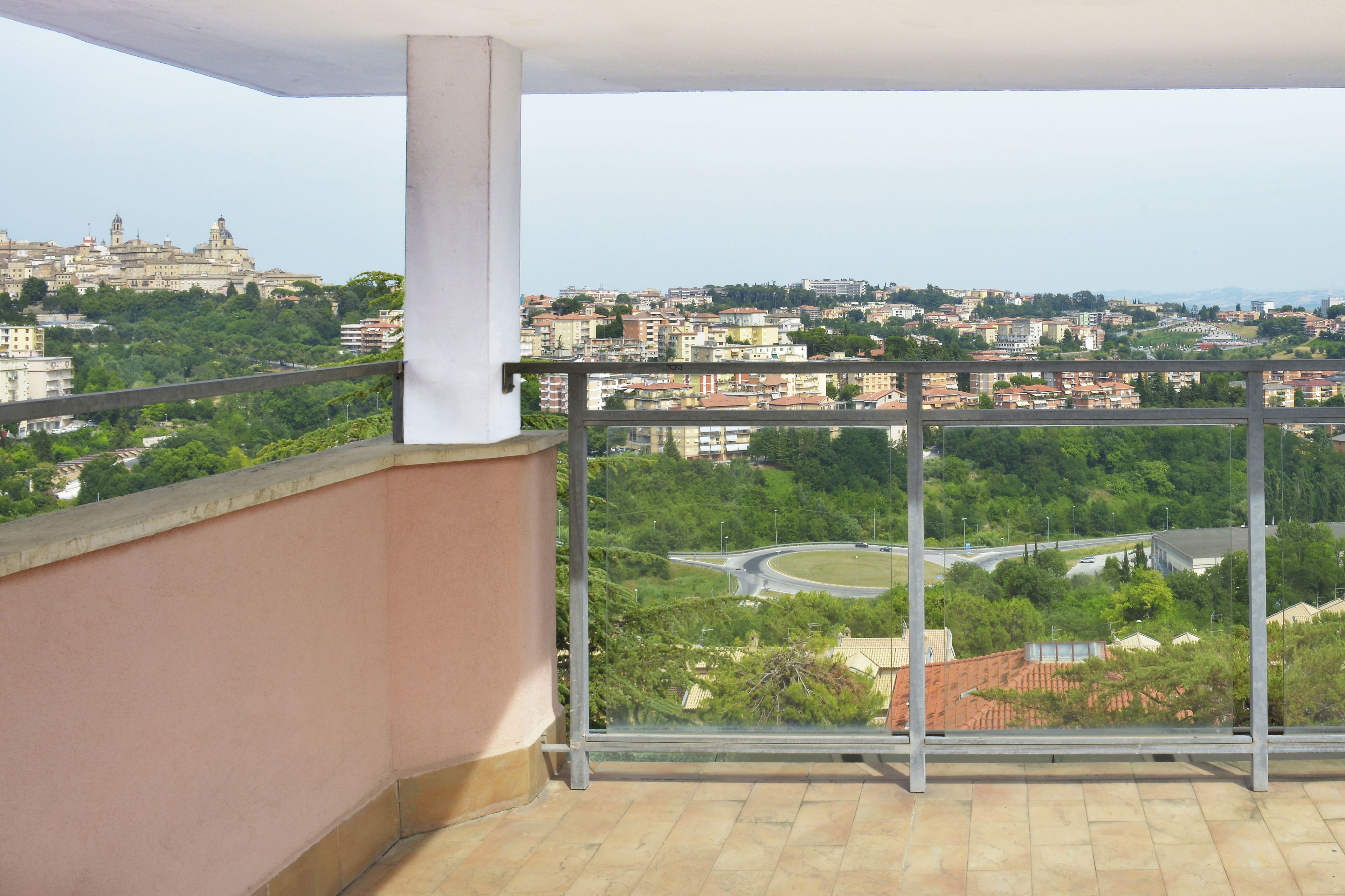 A balcony with a view of a cityscape, including a prominent building in the distance.