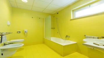 Un bany amb rajoles grogues, una banyera, un lavabo i un vàter.