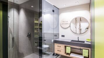 A modern bathroom with a glass shower enclosure, a sink with a mirror, and a toilet.