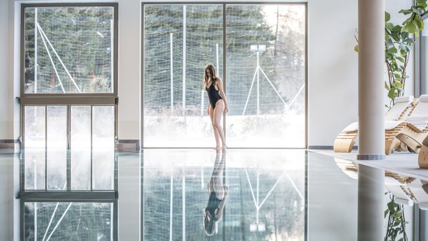A spacious indoor area with a large glass window, a person standing, and a reflection on the floor. - Sporthotel Zoll (Vipiteno)