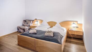 A neatly arranged bedroom with a wooden bed, a small sofa, two bedside tables with lamps, and a nightstand.