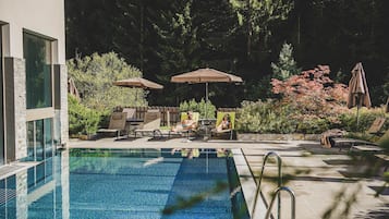 Een binnenzwembad, een buitenzwembad en parasols bij het zwembad