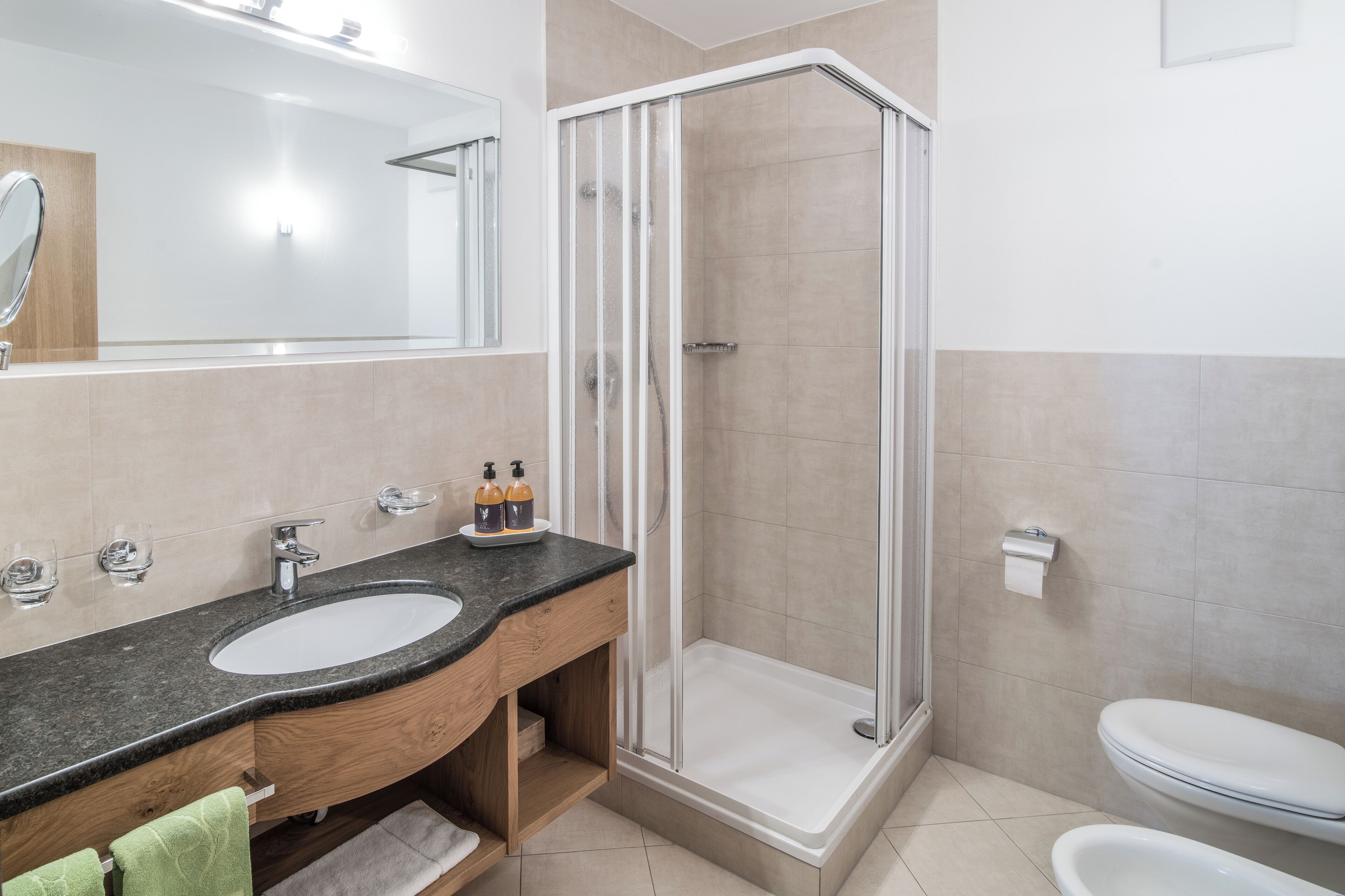 Un baño moderno con lavabo, espejo, ducha e inodoro.