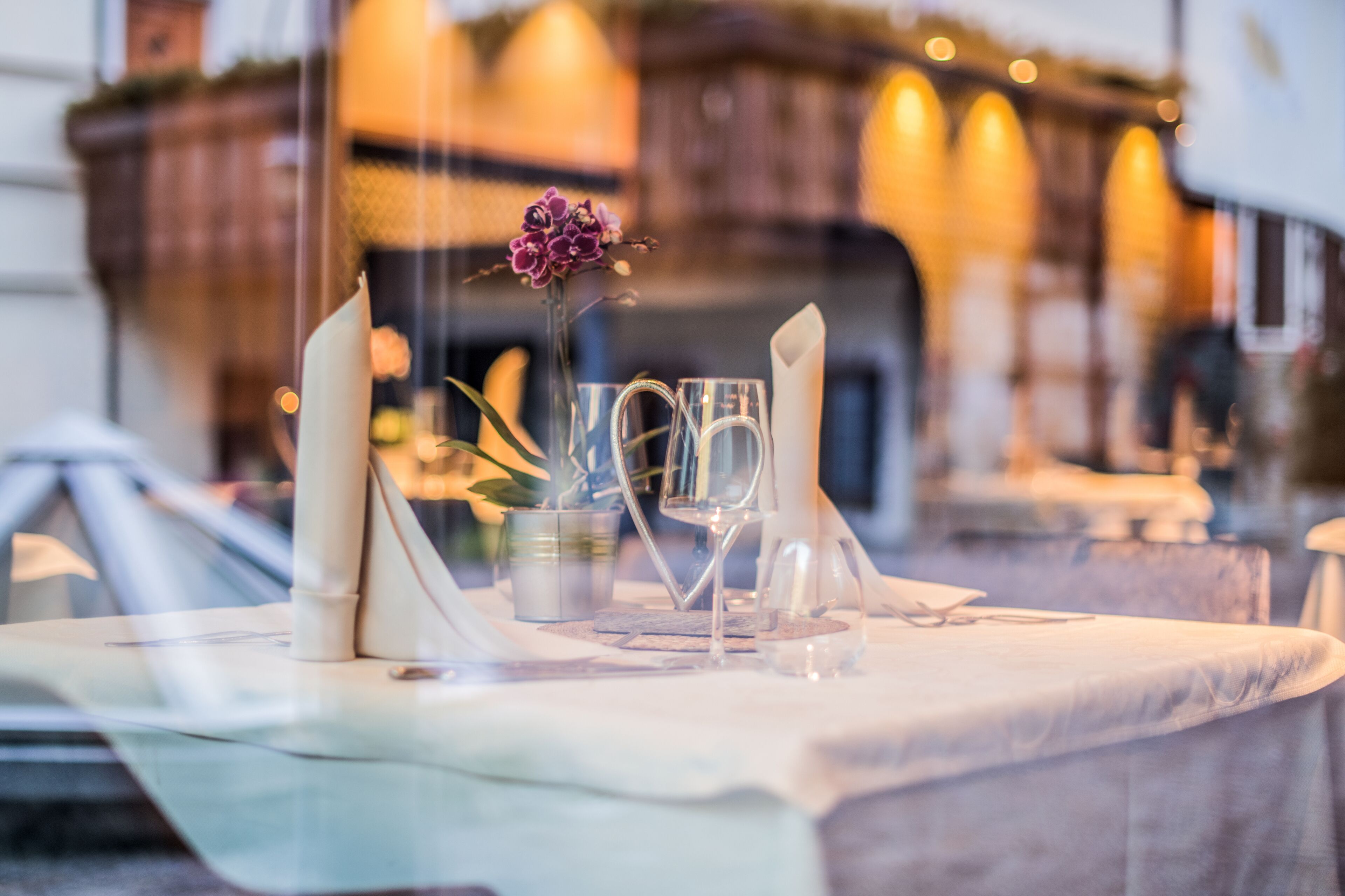 A table set with a clear glass, a candle, and a flower.