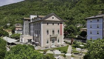 Un hotel con patio, mobiliario exterior y un letrero de jardín.