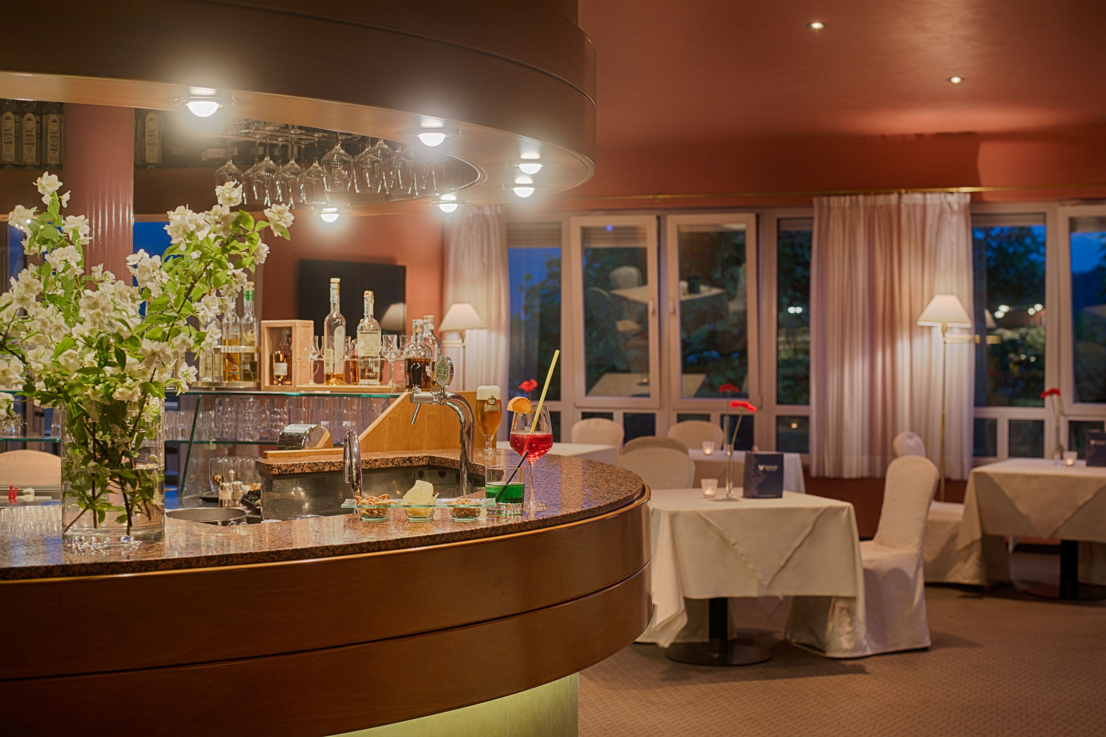 A bar area with a counter, bar stools, and a dining area with tables and chairs.